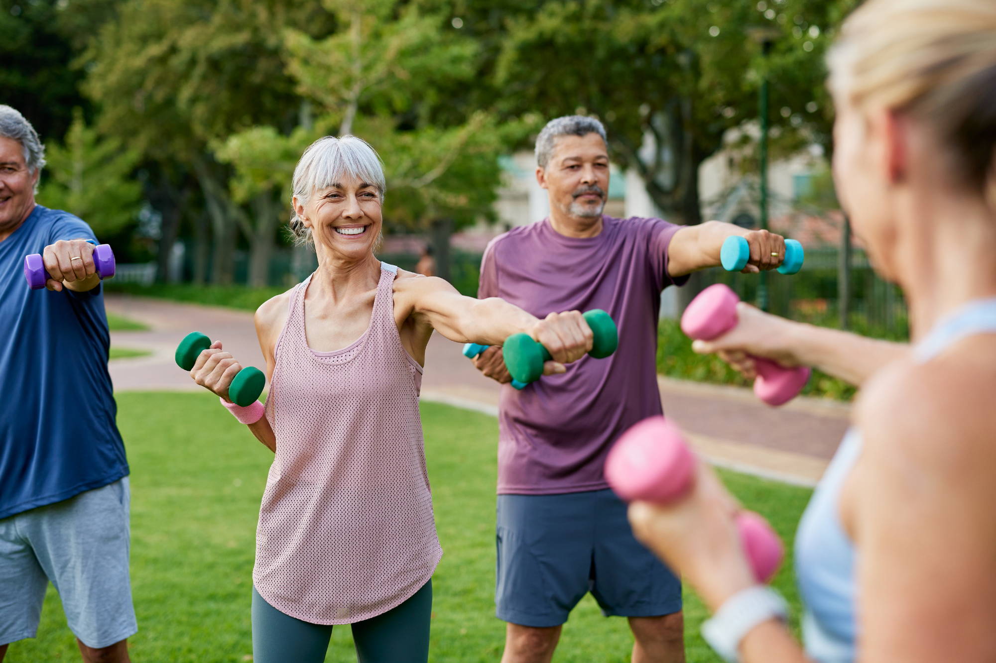 Gruppe von Seniorinnen und Senioren beim fröhlichen Ganzkörpertraining im Park